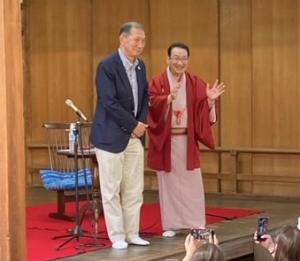 壇上に立つスーツ姿の男性と着物姿の男性