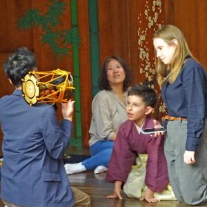 鼓を叩く男性を見つめる外国人の男の子と女性