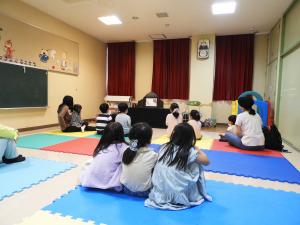 室内でお話しを聞く子どもたちの後ろ姿
