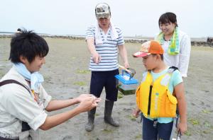 干潟で発見した生物を観察する、子どもと大人