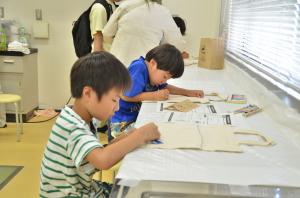 鞄に絵を描く子ども二人