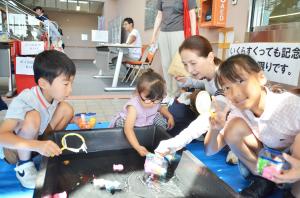 金魚すくいをする子ども三人と大人一人
