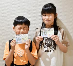 自分がみつけたチリメンモンスターを貼ったカードを持つ小学生の姉弟