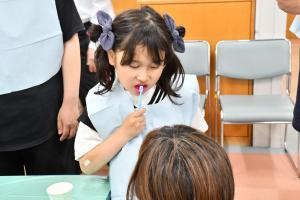 赤い薬剤を使って歯磨き指導を受ける女の子