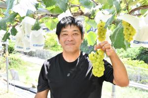 ぶどうを手に持って笑顔の井出さん