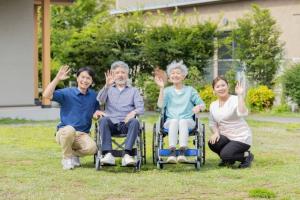 車いすの方としゃがんでいる方4人が手を振る