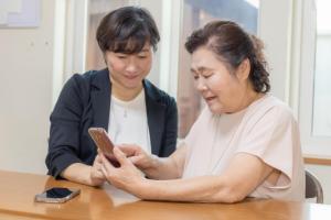 講師にスマホの操作を習う高齢女性