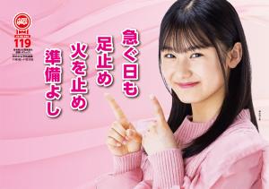 ピンクのセーターを着た若い女性が「急ぐ日も 足止め 火を止め 準備よし」と書かれた標語を指さすポスター