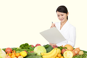 野菜やくだものを前に何か考えている様子の女性の栄養士