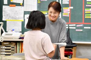 女子児童に優しく微笑みかける女性の支援員