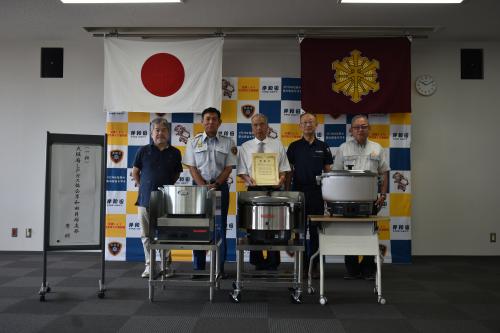 デリバリーステーション一式を寄贈してくれた一般社団法人大阪府Ｌｐガス協会岸和田貝塚支部様と消防長の写真