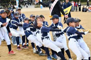 綱引きをする野球のユニフォームを着た小学生の男の子たち