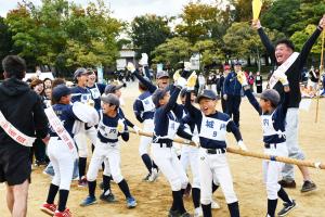 綱引きで勝って万歳をして喜ぶ城内校区の子どもたちと応援の男性