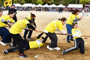 綱引きでこけて引きずられる男の子と笑う女性たち
