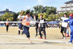 校区対抗リレー、テープを切ってゴールする男性