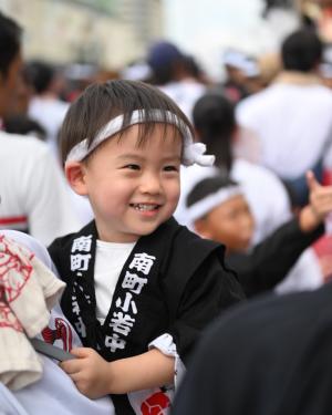 鉢巻をまき、法被を着た笑顔の子ども