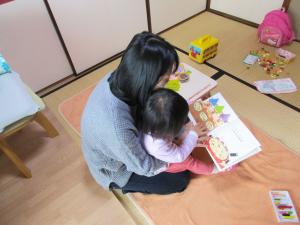 膝の上で本を見る幼児