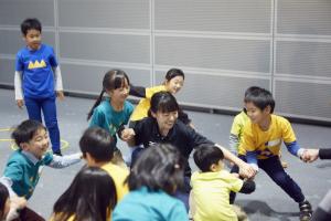 手をつなぎ先生と遊ぶ子供たち