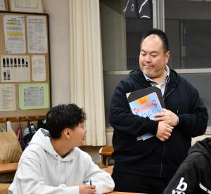 授業中、質問する男子生徒と笑顔で答える先生