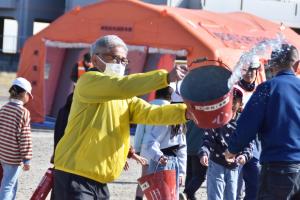 バケツの水を火元にかけて初期消火活動をする男性