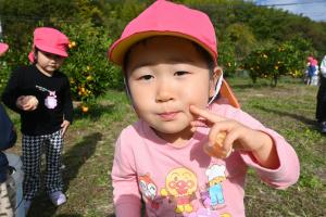 口にみかんを頬張っている園児