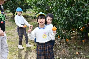 笑顔でみかんを持っている園児