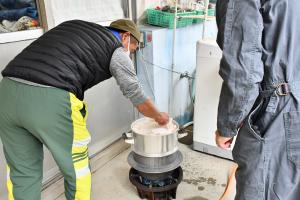 蒸し上がったもち米を鍋から取ろうとする地域の男性