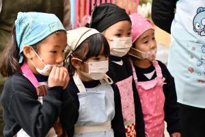 大人たちが力強くもちをつく様子を見守る子どもたち