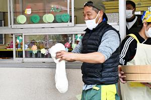 伸びたおもちを子どもたちに見せる地域の男性