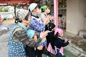 拍手をして喜ぶ子どもたちと保護者、先生たち