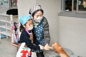 おばあちゃんと一緒にもちをつく女の子