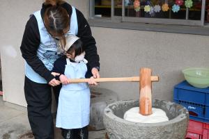 お母さんと一緒にもちをつく女の子