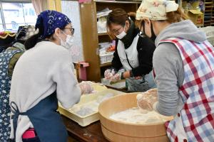 つきあがったおもちをちぎって丸める保護者の方々