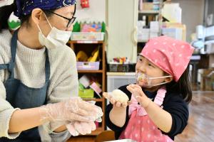 お母さんと一緒におもちを丸める女の子