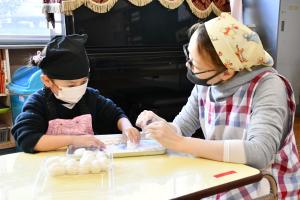 お母さんと一緒におもちを丸める女の子