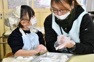 お母さんと一緒におもちを丸める女の子