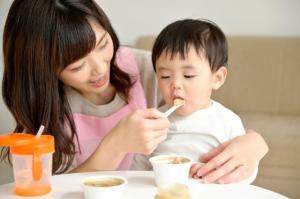 お母さんが子どもに離乳食をスプーンで食べさせている様子