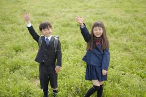 右手を挙げる小学生の男女