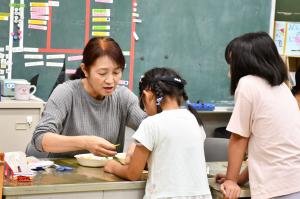 支援員の女性が小学生に指導している様子