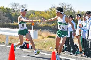 男子高校生のランナーがたすきを渡すところ