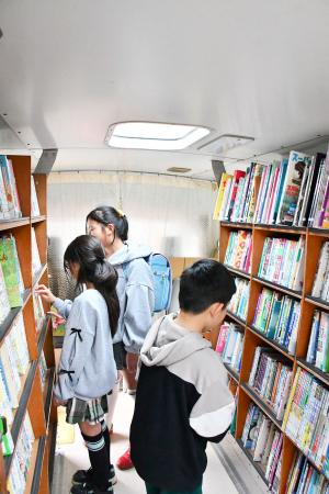 自動車文庫の車内で本を選んでいる写真