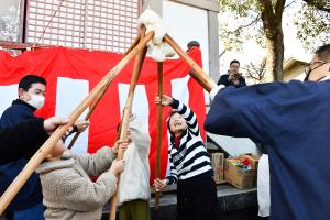 ついた餅を高く上に掲げる人たち