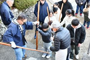 長い棒状の杵を受け取る子ども