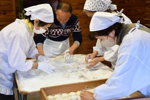お持ちを丸める白い割烹着姿の女性たち