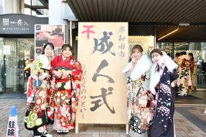 成人式の看板前に並ぶ振り袖姿の4人の女性