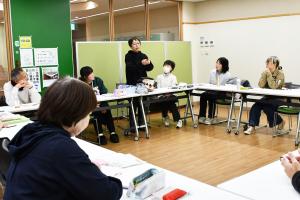 立って話す女性を見る人たち