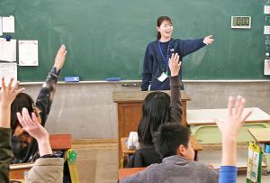 質問に手を挙げる児童と教壇で笑顔の女性の講師