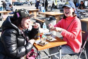 美味しそうに蒸し牡蠣を食べる女性二人