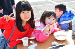 美味しそうに牡蠣ラーメンを食べる幼い女の子と隣でピースをするお姉ちゃん