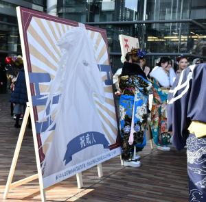 今年の干支である午が描かれたデザイン看板の前で撮影する二十歳の方々